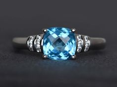 a blue topazte and diamond ring on a black surface with white gold accents