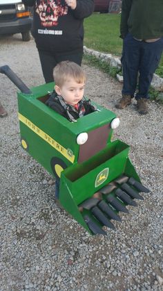 a young boy in a green toy tractor