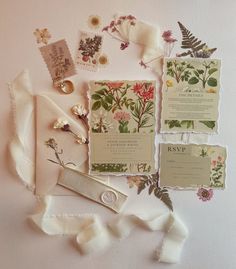 the wedding stationery is laid out on top of each other with ribbons and flowers