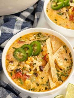 two white bowls filled with chicken tortilla soup and garnished with green peppers