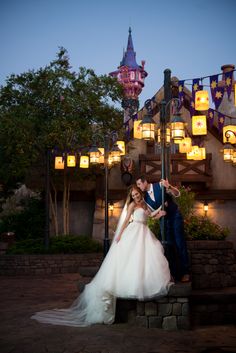 a bride and groom pose for a photo in front of the sleeping beauty castle at night