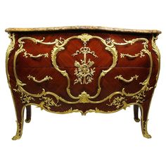 an ornately decorated chest with gold trimmings on the top and bottom drawers