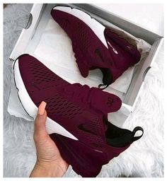 someone is holding up their maroon nike shoes in a box with the bottom part open