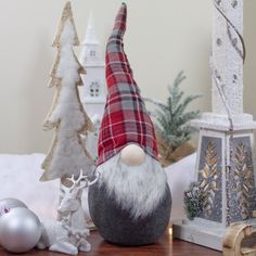 a gnome figurine sitting on top of a table next to christmas trees