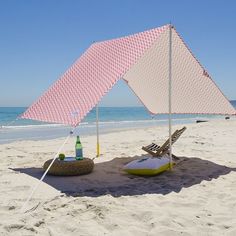 a pink and white umbrella sitting on top of a sandy beach