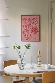 two vases with flowers sit on a round table in front of a pink painting