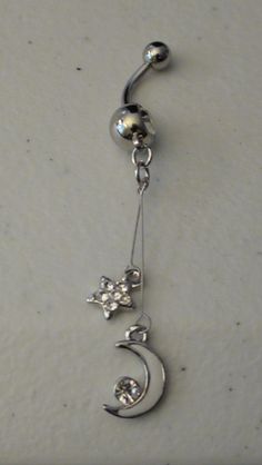 a dangling belly ring with flowers and stars on the bottom, hanging from a hook