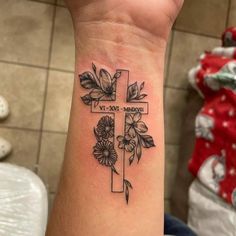 a cross with flowers and leaves on the wrist is shown in this tattoo style photo