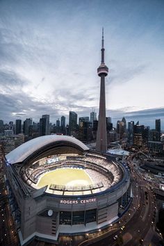 an aerial view of the hockey stadium in front of the city skyline at dusk, toronto