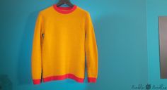 a yellow and red sweater hanging on a blue wall next to a mirror in a room