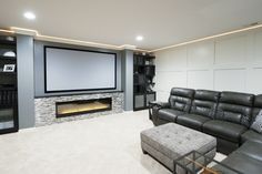 a living room with a large screen tv and couches in front of the fireplace