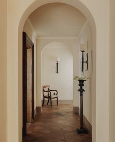 an archway leading to a hallway with a chair and vase