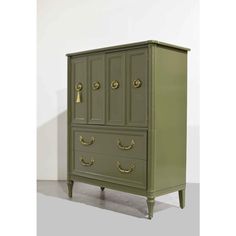 an antique green armoire with brass handles and knobs on the doors, in front of a white wall