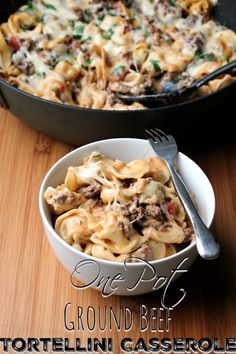 a casserole dish with ground beef and tortellini in it on a wooden table