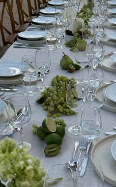 a long table is set with plates, silverware and limes for an elegant dinner