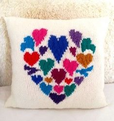 a white pillow with multicolored hearts on it