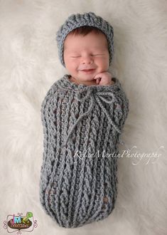 a newborn baby wrapped in a gray knitted blanket