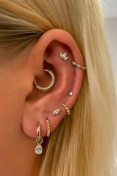 a blonde woman wearing ear piercings with diamonds on her left ear and an ear cuff