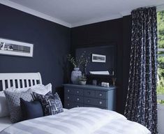 a bedroom with black walls, white bedding and blue drapes on the windowsill