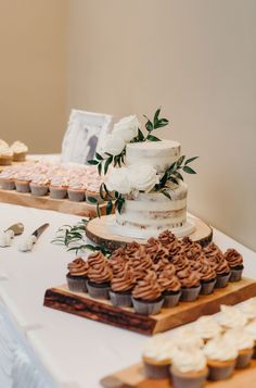 a table topped with lots of cupcakes next to a cake and other desserts