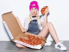 a woman sitting on the floor holding up two slices of pizza