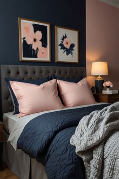 a bed with blue and pink sheets, two framed pictures on the wall above it