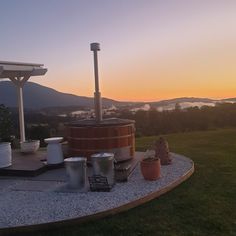 a hot tub sitting on top of a lush green field next to a lake at sunset