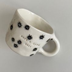 a white coffee cup with black spiky designs on the outside and inside it