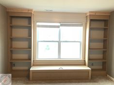 an empty room with some bookshelves and a window in the corner that has no curtains