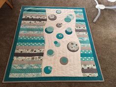 a blue and white quilted table runner on the floor with circles, dots and stripes