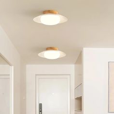 two lights that are on the ceiling in a room with white walls and wood flooring