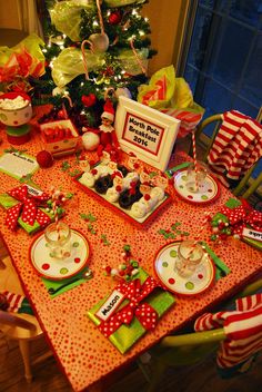 a dining room table set for christmas dinner with plates, cups and utensils