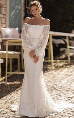 a woman in a white wedding dress posing for the camera with her hands on her hips