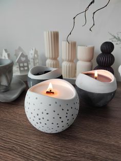 two white candles sitting on top of a wooden table next to vases and other decorative items