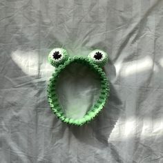 a close up of a green frog shaped object on a bed