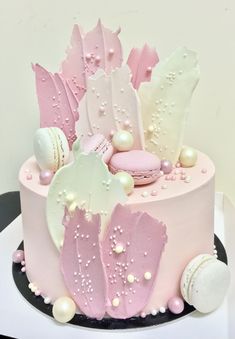 a pink and white cake decorated with seashells, pearls, and other things