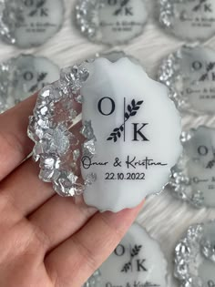 a person holding up a ring made out of ice and glass crystals with the words ok on it