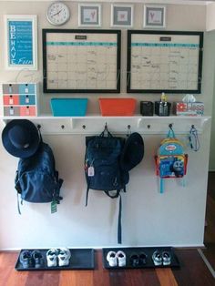 two backpacks are hanging on the wall with other items in front of them,