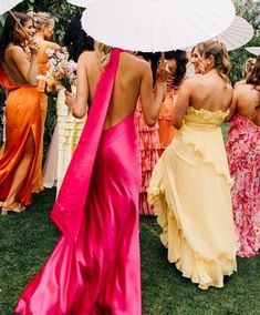 a group of women standing next to each other holding umbrellas in their hands and wearing dresses