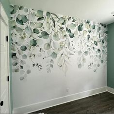 an empty room with painted leaves on the wall and wood flooring in front of it