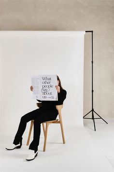 a woman sitting in a chair holding up a sign