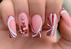 a woman's hand with red and white nail polishes on it, decorated with candy canes