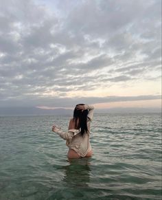 a woman standing in the water with her arms up