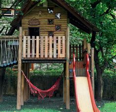 a wooden play house with a slide and basketball hoop in the backgroung