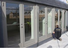 a man walking past a building with glass doors on it's sides and windows reflecting the sky