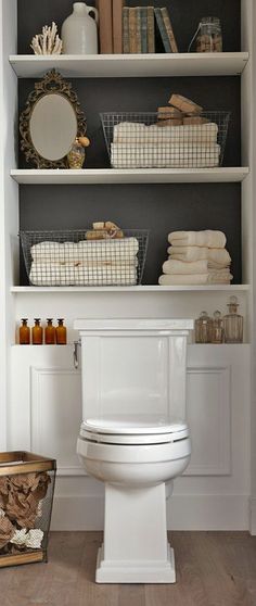 a white toilet sitting inside of a bathroom next to a shelf filled with towels and other items