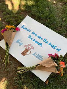 flowers are placed on the ground next to a sign that says thank you all the best