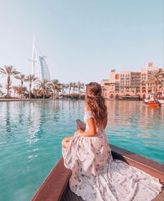 a woman sitting in a boat looking out at the water and palm trees around her