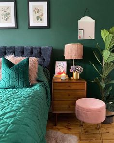 a bedroom with green walls and a bed covered in blue velvets, pillows and blankets