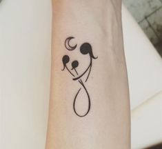 a small black and white dog tattoo on the wrist